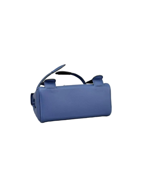 A small blue leather handbag with a top handle, photographed on a plain light gray studio background.