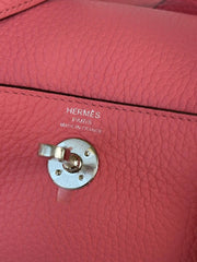 Close-up of a pink Hermès handbag with visible branding.