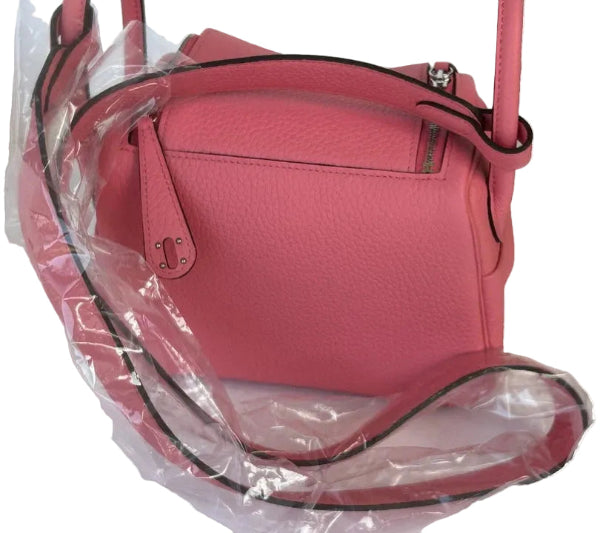 Pink handbag with clear plastic wrap and an orange box on a white background