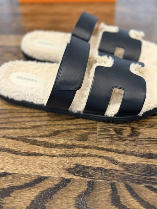 Pair of black and beige slippers on a wooden floor