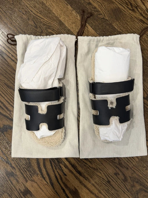 Pair of white shin guards with black straps on a wooden surface