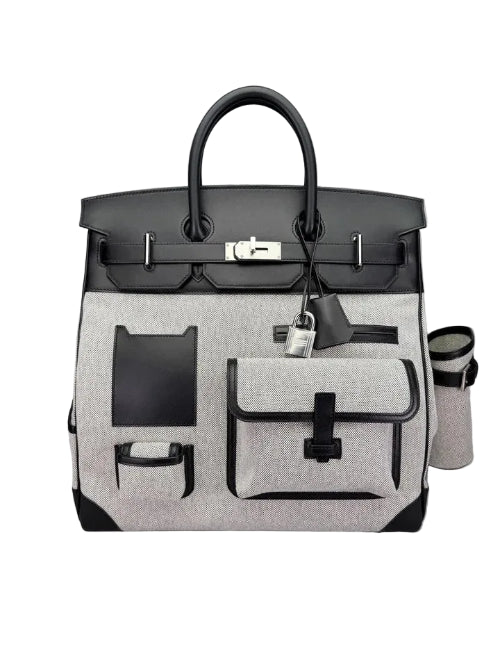 A structured black and white leather handbag with silver-tone hardware, featuring a top handle, front flap pocket, and zippered side pocket, photographed on a plain white background.