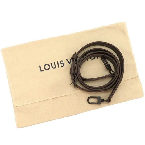 Louis Vuitton brown leather strap on a beige cloth with 'LOUIS VUITTON' branding.
