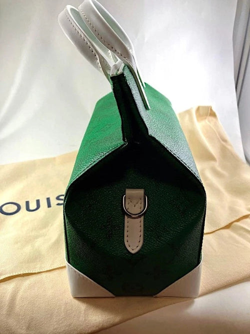 Green handbag with a white strap on a beige surface