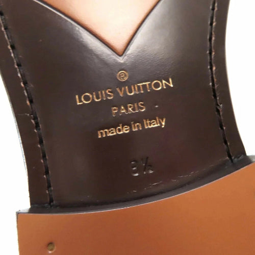 Louis Vuitton leather product with gold lettering on a brown background