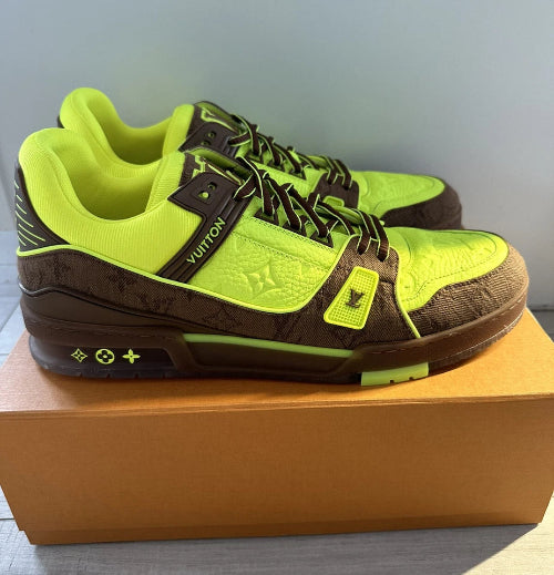 Pair of brown and green sneakers on a box with a neutral background
