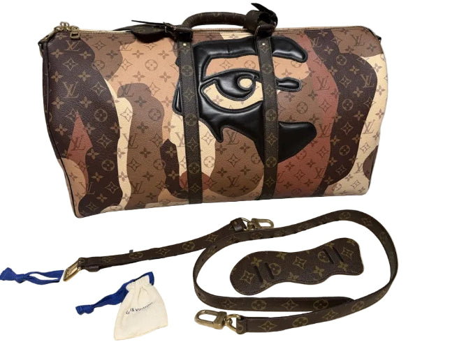 Designer handbag with artistic design and strap on a gray surface