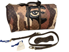 Designer handbag with artistic design and strap on a gray surface