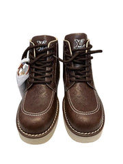 A pair of brown leather lace-up boots with white rubber soles, shown against a neutral gray background.