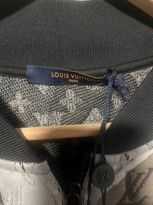 Close-up of a black leather bag with a visible brand logo on a wooden surface.