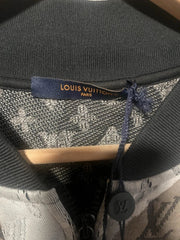 Close-up of a black leather bag with a visible brand logo on a wooden surface.