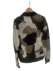 Camouflage-patterned jacket on a wooden hanger against a white wooden panel background