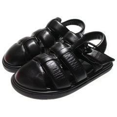 Black leather sandals with strap details on a white background