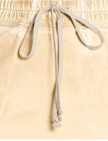 Close-up of beige drawstring shorts showing the elastic waistband and light beige drawstring cords tied at the front.