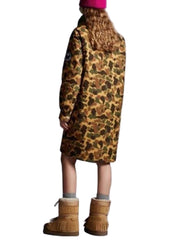 Person wearing a leopard print coat and brown boots on a plain background