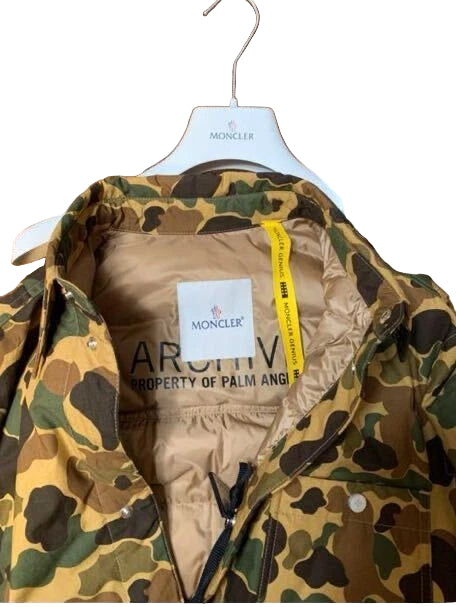Camouflage jacket with Moncler and Palm Angels labels on a hanger.