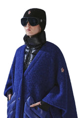 Person wearing a blue coat with a brand logo in a snowy mountain setting