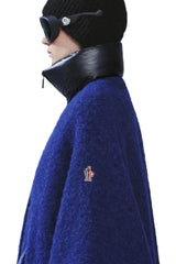 Person wearing a blue coat with a brand logo against a mountainous background
