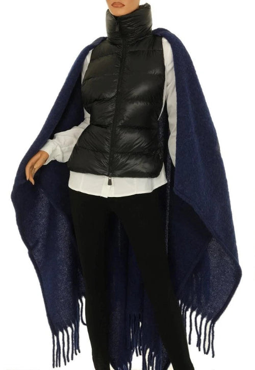 Person wearing a black puffer vest and navy blue fringed poncho on a white background