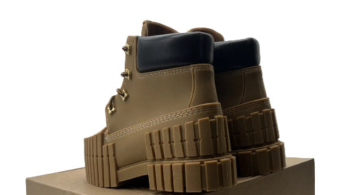 Tan boots stacked on a cardboard box with a visible brand label.