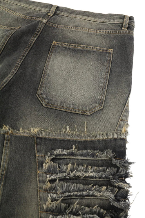 Close-up of distressed denim jeans with frayed edges on a white background