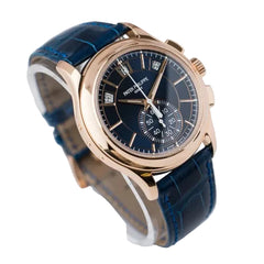 Luxury watch with blue strap and rose gold case on a light gray background