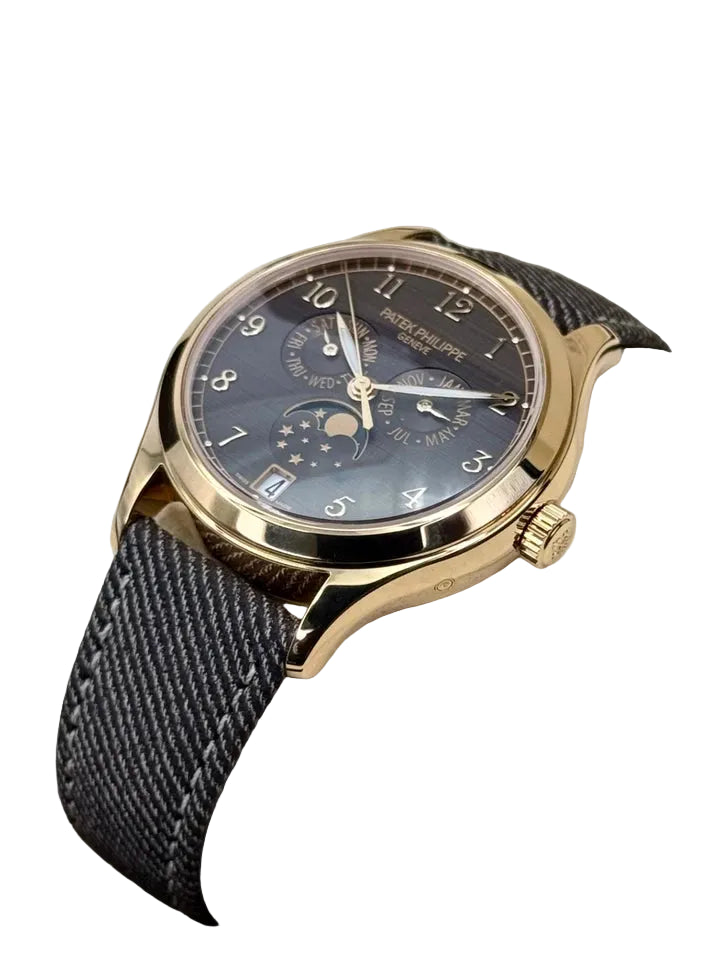 Luxury watch with gold case and dark strap on a white cushion