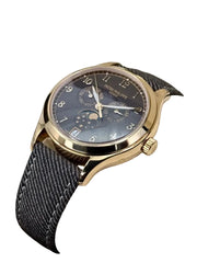 Luxury watch with gold case and dark strap on a white cushion