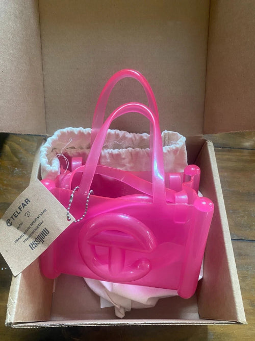 Pink plastic bag with handles in a cardboard box on a wooden surface