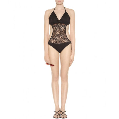 A model wearing a black lace halter neck one-piece swimsuit with a deep V-neckline and cutout details, paired with black strappy sandals against a plain white background.