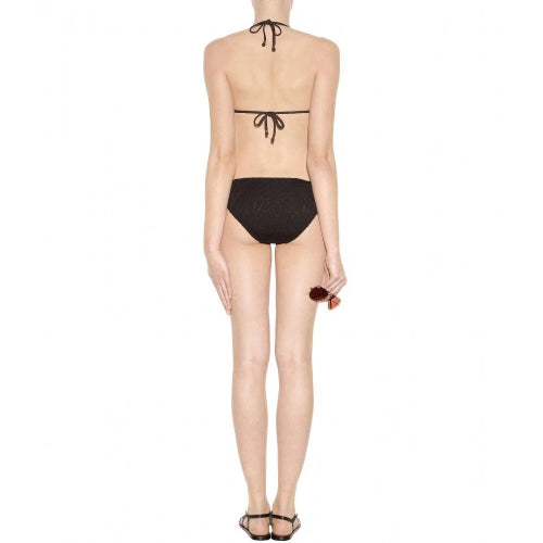 A model shown from the back wearing a black string bikini with a halter-style top and high-cut bottoms, paired with black strappy heels against a plain white background.