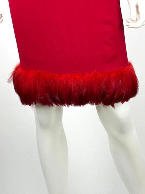 A bright red dress or skirt displayed on a white mannequin, featuring a smooth red upper section and a voluminous red feathered hem against a plain white background.