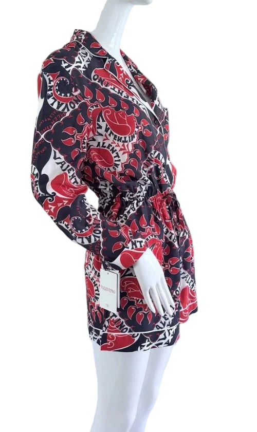 Mannequin wearing a patterned dress with red, black, and white design on a plain background