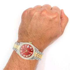 Wrist wearing a watch with a red face and gold accents on a white background