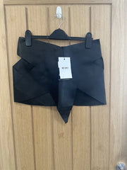 Black top with a tag on a wooden hanger against a wooden background