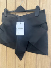 Black garment on a hanger with a visible tag on a wooden surface