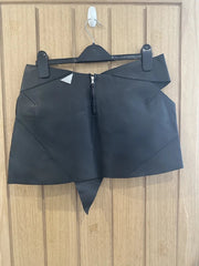 Black leather skirt on a hanger against a wooden panel background