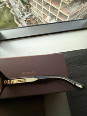 Tom Ford sunglasses with case on a reflective surface with a window view in the background