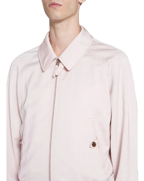 A close-up of a model wearing a light pink zip-up jacket with a pointed collar and a zippered chest pocket.