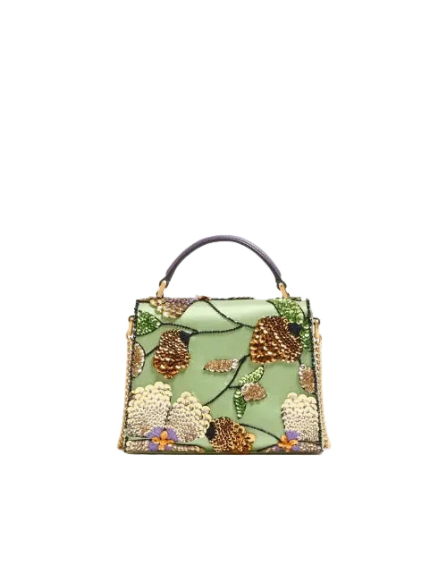 A structured light green handbag with an intricate floral and botanical beaded design in gold, brown, and cream, featuring a dark purple top handle.