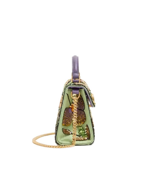 A small structured handbag in light green leather with a gold chain strap, purple top handle, and a large embroidered floral motif in purple, gold, and green on the front, shown against a plain white background.