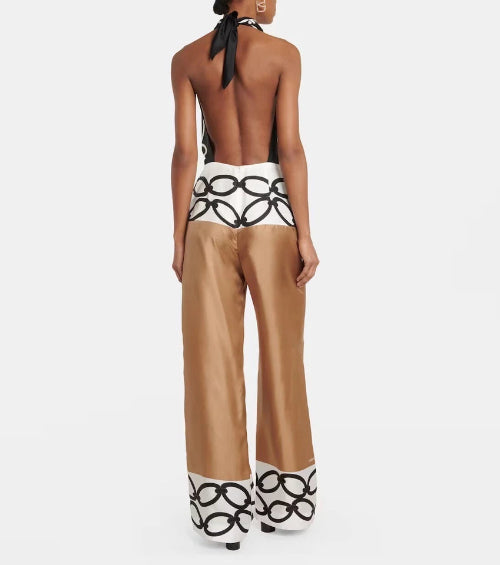Woman wearing a black and white patterned top and tan pants with black and white designs on a white background