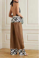 Woman wearing a brown dress with black and white patterned details in an elegant room.