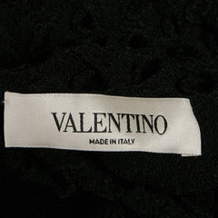 A close-up of a black textured garment with a white Valentino brand label reading 'VALENTINO MADE IN ITALY'.