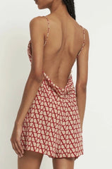 Woman wearing a red and white patterned dress with thin straps on a plain background