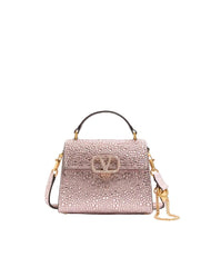 Pink handbag with gold chain on a light pink background