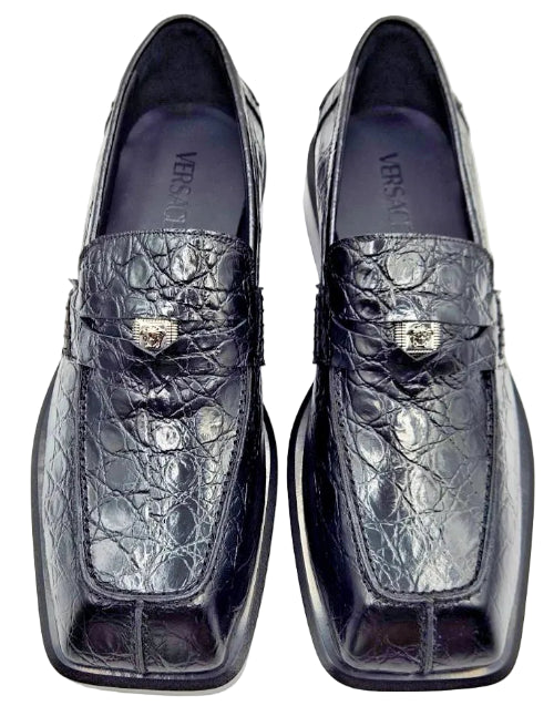 Pair of black crocodile skin loafers on a white background
