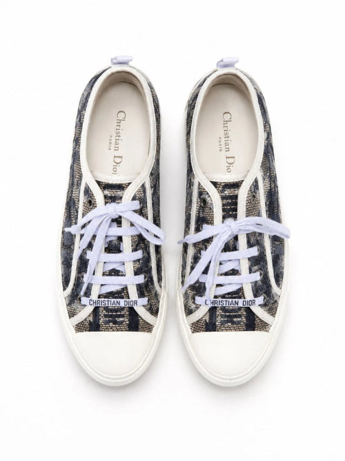 A pair of low-top canvas sneakers in black and white with white laces, photographed from a top-down angle on a white background.