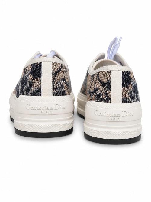 A pair of low-top sneakers shown from the back, featuring a black and white abstract patterned upper with white midsoles and white laces.