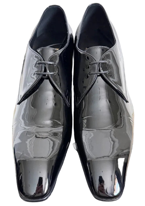 A pair of men's black leather dress shoes with a glossy finish, featuring a classic oxford style with a closed lacing system and a pointed toe, displayed on a dark gray background.